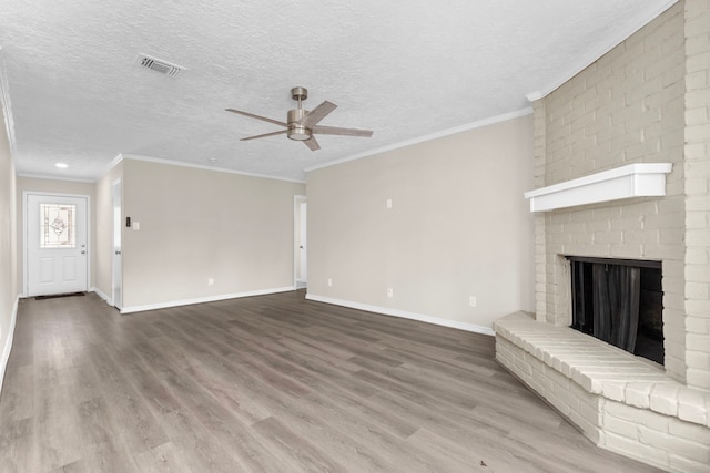 unfurnished living room featuring a fireplace, visible vents, a textured ceiling, wood finished floors, and baseboards