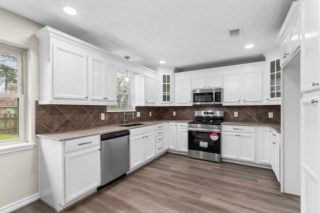 kitchen featuring dark wood-style flooring, stainless steel appliances, glass insert cabinets, white cabinets, and a sink