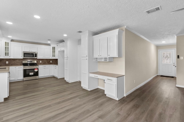 kitchen featuring glass insert cabinets, white cabinetry, appliances with stainless steel finishes, and built in study area