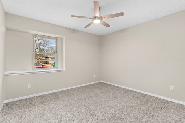 carpeted spare room with ceiling fan and baseboards