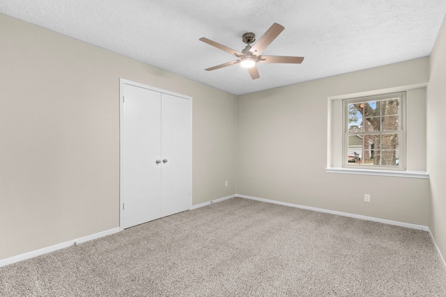 unfurnished bedroom featuring a textured ceiling, carpet floors, a closet, and baseboards