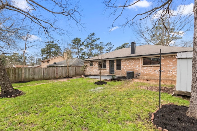 back of property featuring a yard, brick siding, cooling unit, and fence