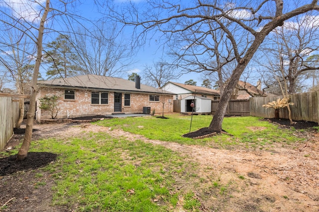 back of house with a yard, brick siding, central AC unit, and a fenced backyard