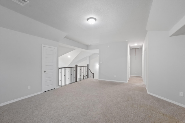 bonus room with light colored carpet and a textured ceiling