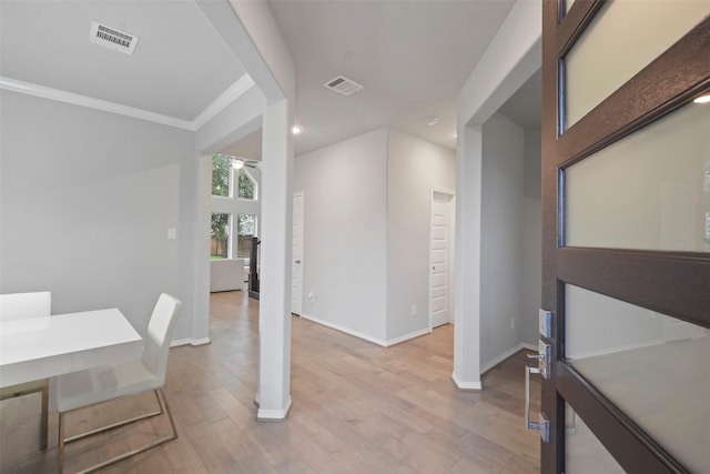 dining space with crown molding and light wood-type flooring