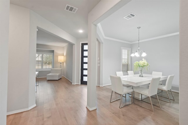 dining area with an inviting chandelier, a wealth of natural light, crown molding, and light wood-type flooring