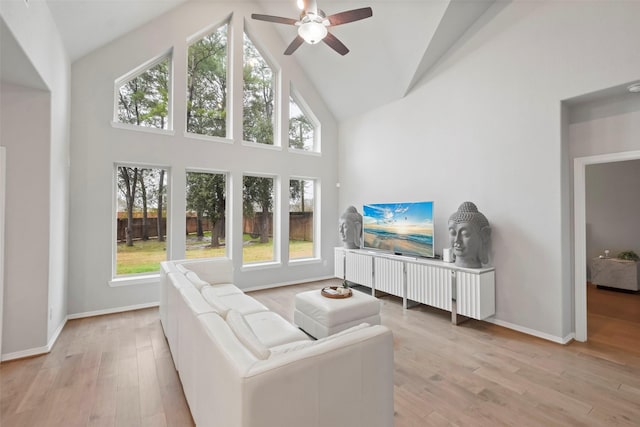 living room featuring plenty of natural light, high vaulted ceiling, and light hardwood / wood-style flooring