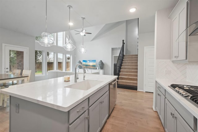 kitchen featuring gray cabinets, sink, backsplash, a kitchen island with sink, and stainless steel appliances