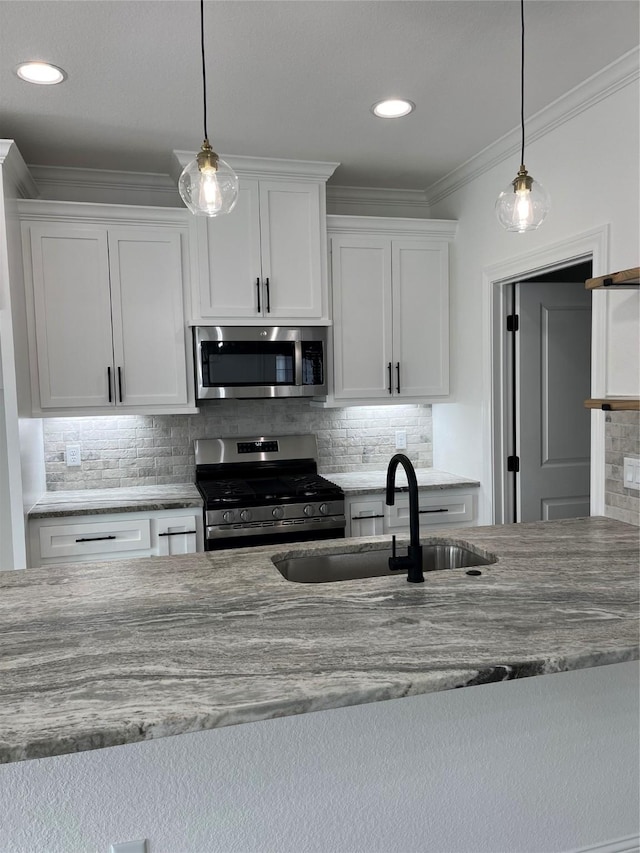 kitchen featuring pendant lighting, sink, crown molding, appliances with stainless steel finishes, and white cabinetry