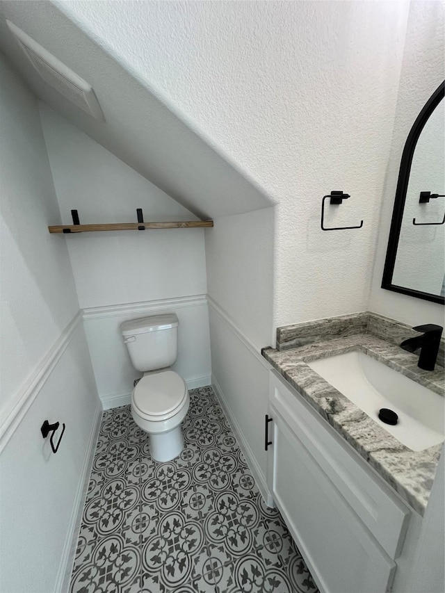 bathroom with vaulted ceiling, vanity, toilet, and tile patterned flooring