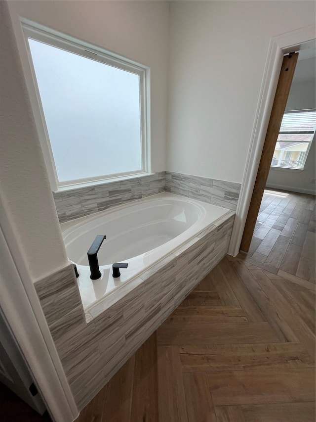 bathroom with parquet flooring and tiled tub