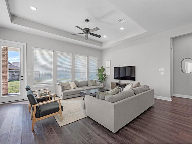 living room featuring dark hardwood / wood-style floors, a tray ceiling, and a wealth of natural light