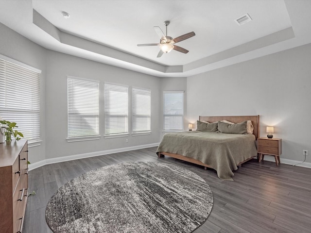 bedroom featuring dark hardwood / wood-style flooring, a raised ceiling, and ceiling fan