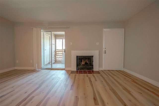 unfurnished living room featuring a brick fireplace and light hardwood / wood-style floors