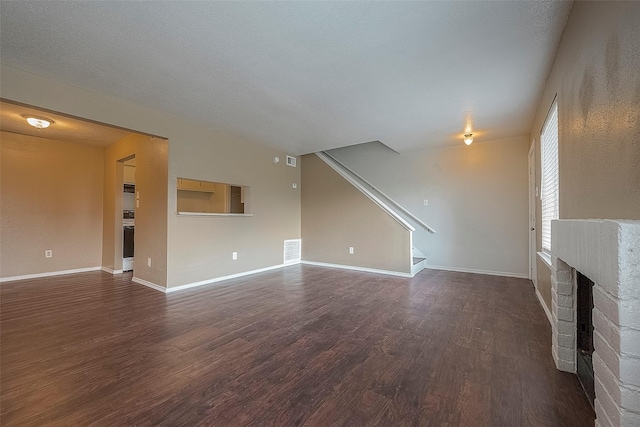 unfurnished living room with a brick fireplace and dark hardwood / wood-style flooring