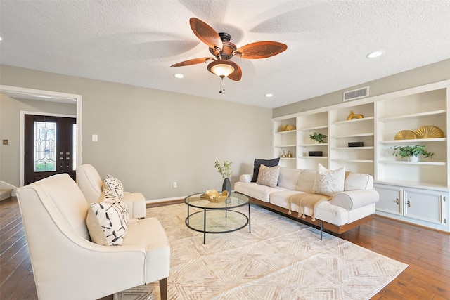 living room featuring ceiling fan, a textured ceiling, and light wood-type flooring