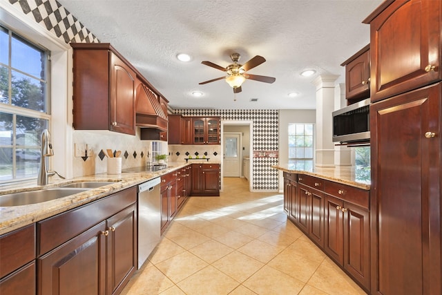 kitchen with sink, stainless steel appliances, a textured ceiling, and light stone countertops