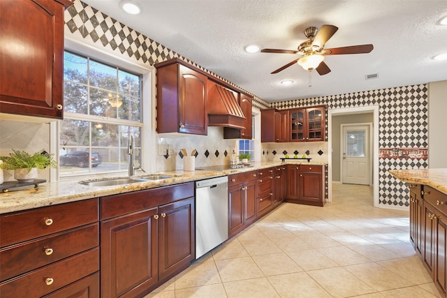 kitchen with sink, a textured ceiling, light stone countertops, and dishwasher