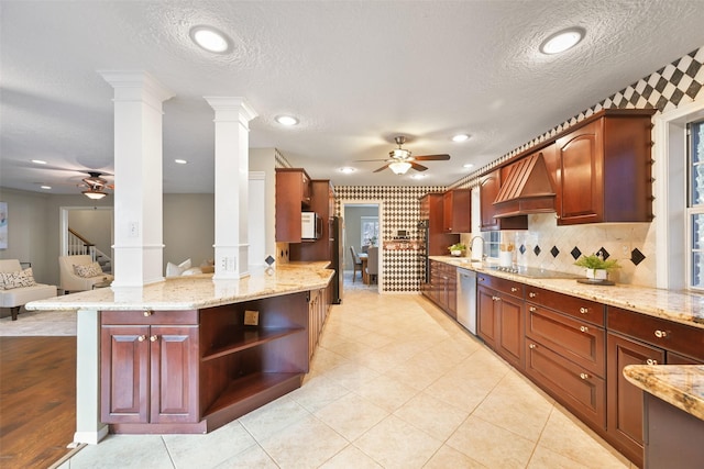 kitchen featuring ornate columns, ceiling fan, stainless steel appliances, light stone countertops, and custom range hood