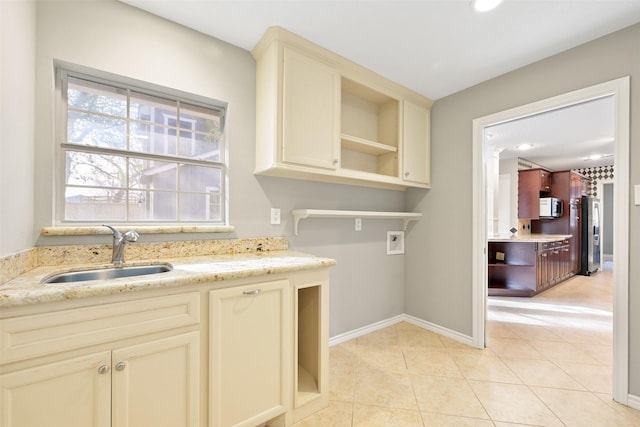 laundry area with cabinets, hookup for a washing machine, sink, and light tile patterned floors