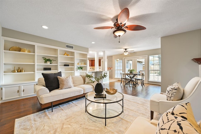 living room with ceiling fan, dark wood-type flooring, and a textured ceiling