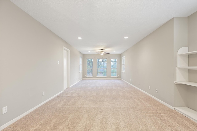 unfurnished living room featuring ceiling fan, light colored carpet, and a textured ceiling