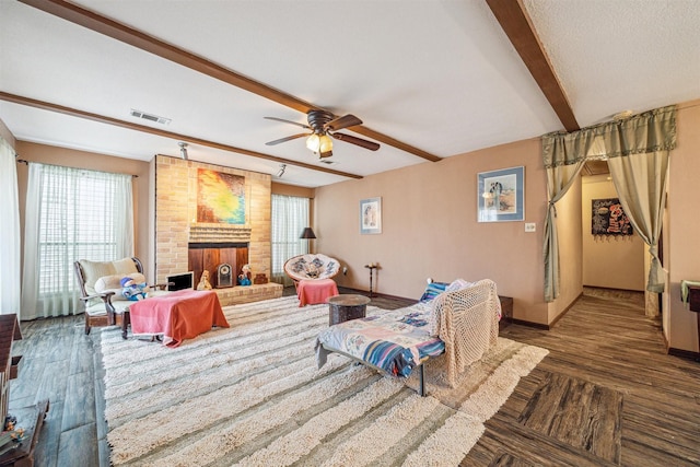 living room with ceiling fan, dark wood-type flooring, a fireplace, and beamed ceiling