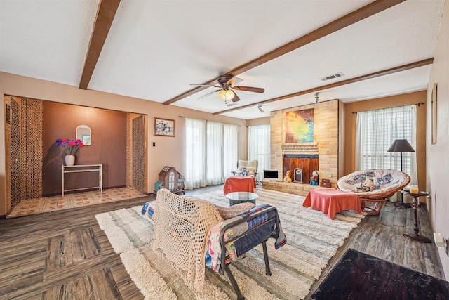 living room featuring beamed ceiling, a brick fireplace, hardwood / wood-style floors, and ceiling fan