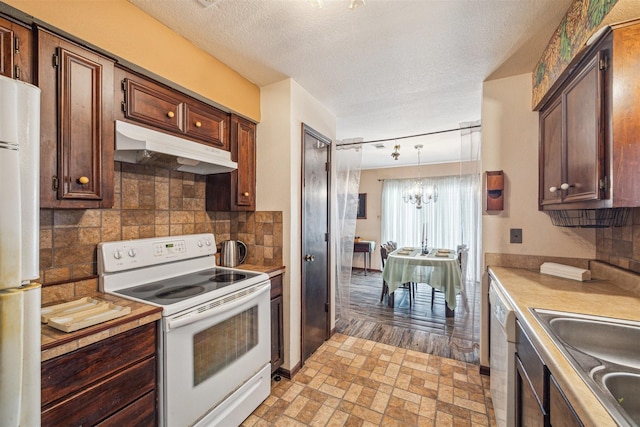 kitchen with sink, an inviting chandelier, hanging light fixtures, white appliances, and decorative backsplash