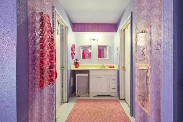 bathroom with tile patterned flooring, vanity, and a textured ceiling