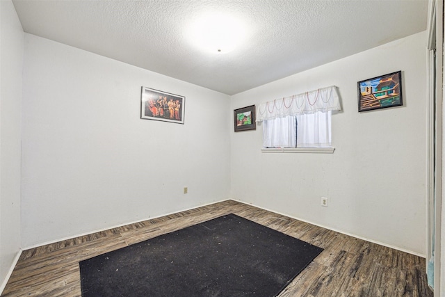 spare room with dark wood-type flooring and a textured ceiling