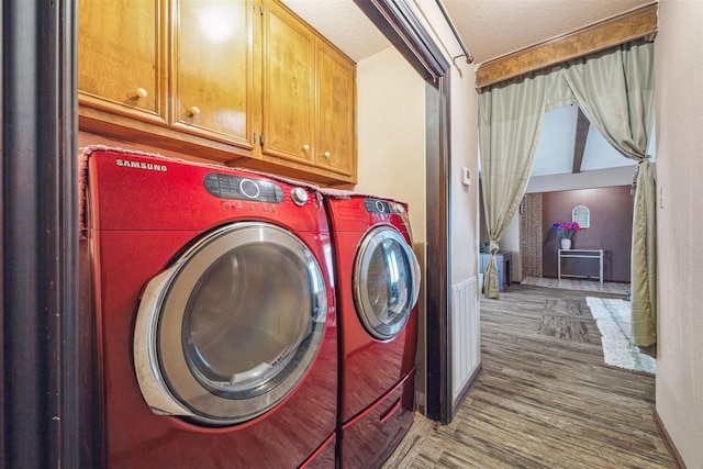 laundry room featuring separate washer and dryer, hardwood / wood-style floors, cabinets, and a textured ceiling