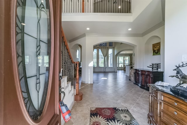 tiled entryway with a high ceiling and ornamental molding