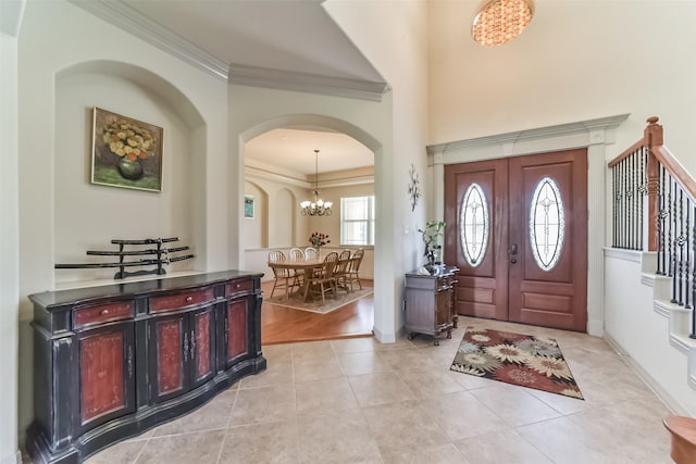 entryway featuring an inviting chandelier, light tile patterned floors, and ornamental molding