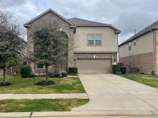 traditional-style home featuring an attached garage, a front lawn, and concrete driveway