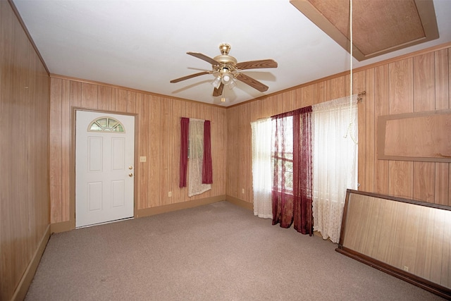 empty room featuring crown molding, light carpet, ceiling fan, and wooden walls