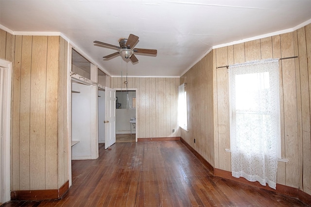 interior space featuring crown molding, dark hardwood / wood-style floors, ceiling fan, and wooden walls