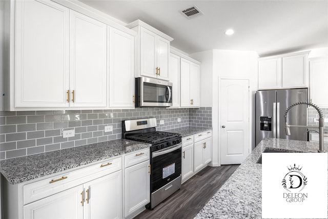 kitchen with stainless steel appliances, white cabinets, light stone counters, and decorative backsplash