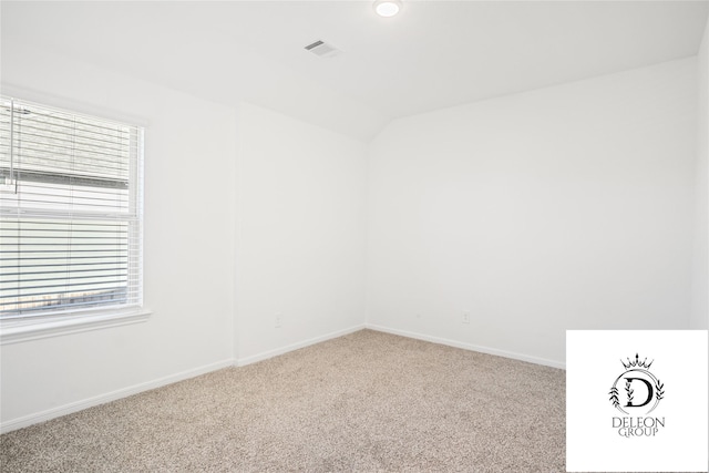 carpeted empty room featuring lofted ceiling