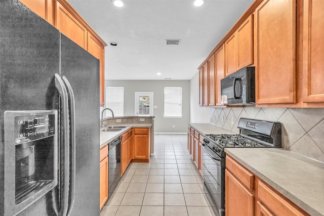 kitchen with light tile patterned flooring, sink, tasteful backsplash, and black appliances