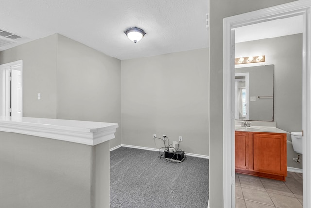 interior space featuring light colored carpet, sink, and a textured ceiling