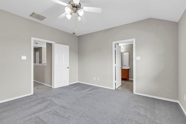 unfurnished bedroom featuring ceiling fan, ensuite bath, vaulted ceiling, and light carpet