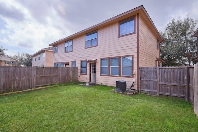 back of house featuring central AC unit and a lawn