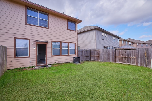 rear view of property with a lawn and central air condition unit