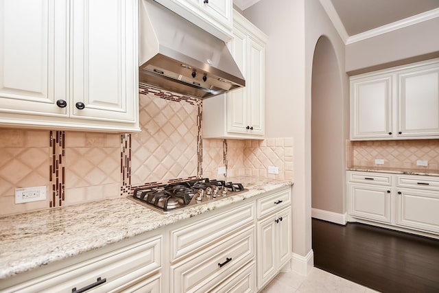 kitchen featuring extractor fan, crown molding, white cabinetry, stainless steel gas stovetop, and light stone countertops