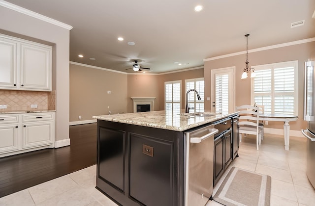 kitchen with white cabinetry, sink, a kitchen island with sink, and crown molding