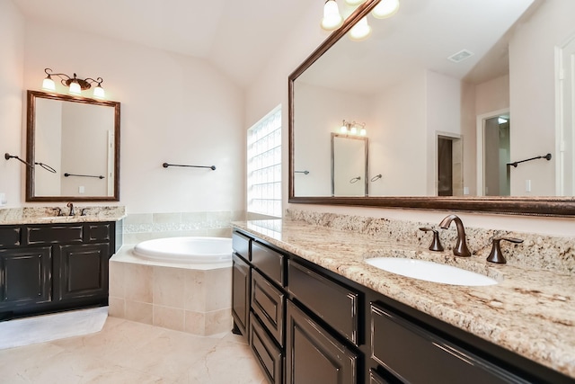 bathroom with a relaxing tiled tub, lofted ceiling, and vanity