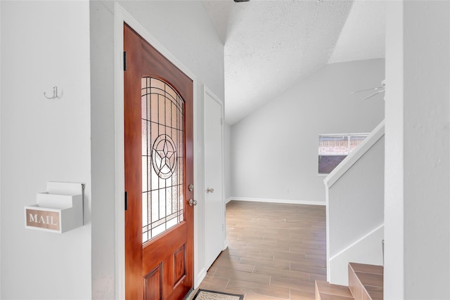 foyer with ceiling fan, lofted ceiling, a healthy amount of sunlight, and a textured ceiling