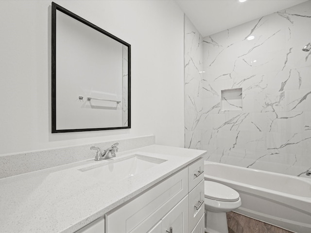 full bathroom featuring hardwood / wood-style flooring, vanity, toilet, and tiled shower / bath combo