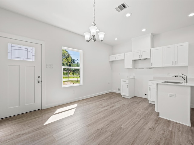 kitchen featuring white cabinetry, sink, pendant lighting, and light wood-type flooring